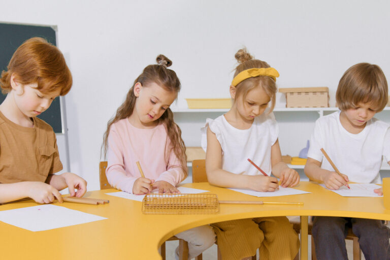 four children writing together at desk