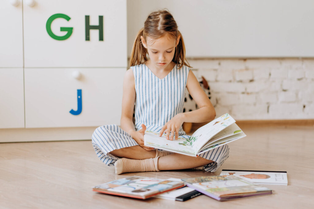 girl sitting on floor reading books
