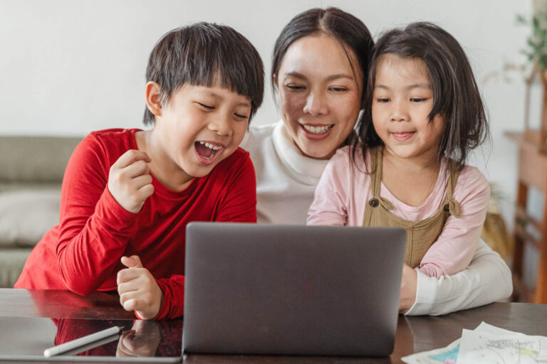 happy mom and kids looking at laptop at home