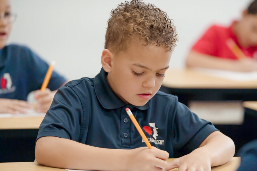 student writing at desk for a spalding activity