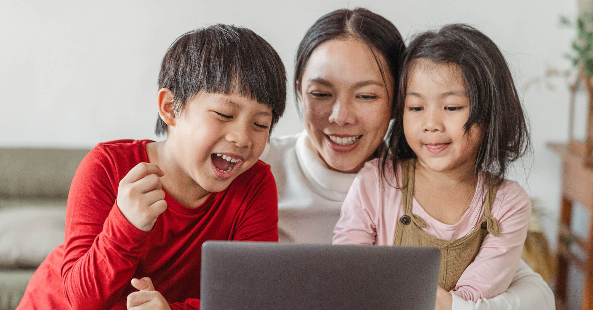 happy mom and kids looking at laptop at home