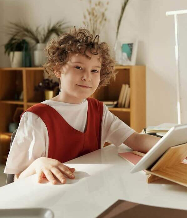 kid looking at the camera while holding a tablet