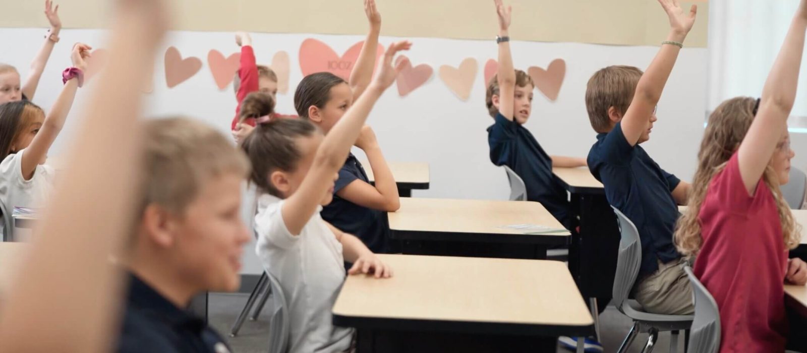 children raising hands in class